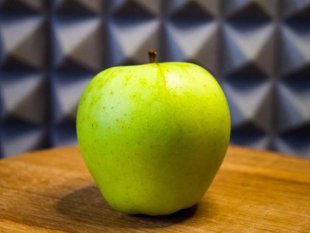 Fresh green apple on wood, symbolizing health and simplicity, ideal for wellness campaigns.の写真素材