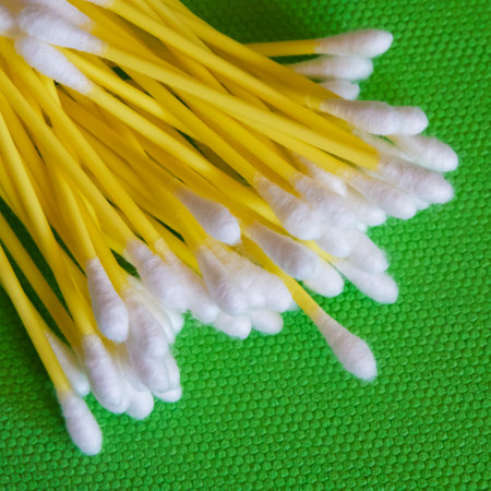 Cleaning Supplies. White-headed cotton swabs, vibrant green setting.の写真素材