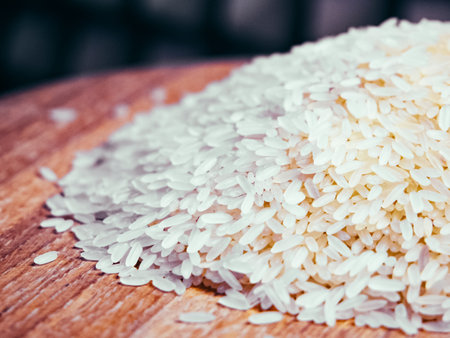 White rice grains piled on wood, blurred background, simple image for cooking or grocery content.の写真素材