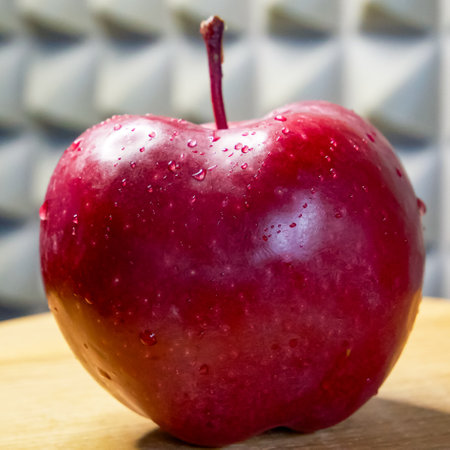 Fresh apple with visible droplets and stem against grey.の写真素材