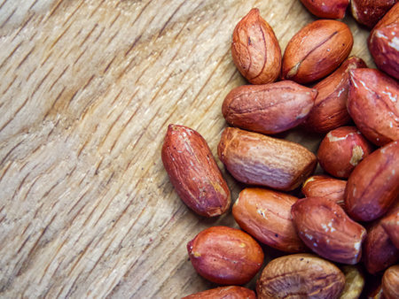 A bunch of peanuts are spread out on a wooden surface. Concept of abundance and variety, as the peanuts come in different sizes and shapes. The wooden surface adds a rustic.の写真素材