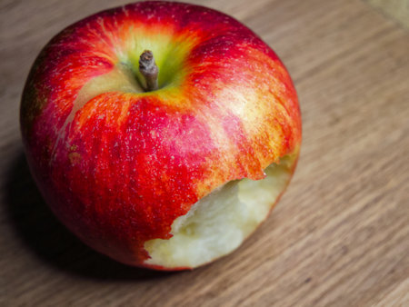 Apple and Wood. An apple with a bite mark, on wood, perfect for illustrating healthy lifestyle or natural food choices.の写真素材