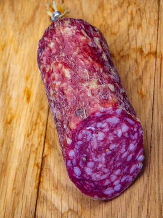 A large piece of smoked sausage on a wooden cutting board, close-up shot. Suitable for food blogs, this image captures the essence of artisanal cured meats.の写真素材