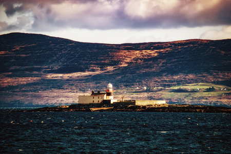 Lighthouse on Rocky Outcrop. A solitary lighthouse stands atop rugged rocks, overlooking the sea.の写真素材