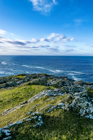 The coastline features dramatic rocky formations and lush greenery, with the ocean stretching far...