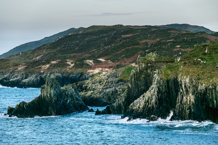Coastal cliffs and serene waters near a rugged landscape in Ireland during a cloudy day.