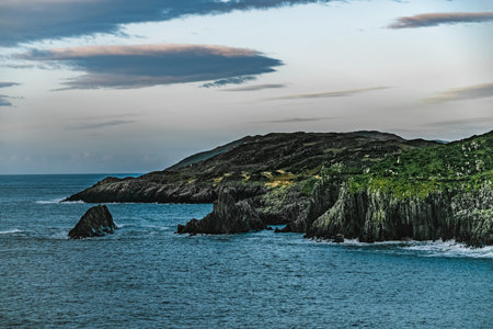 A view of a rocky coastline with a blue ocean. The water has a deep blue color. The sky is clear and...