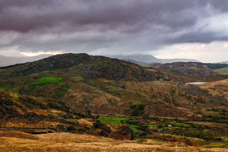 Overcast clouds loom over rugged mountains, revealing a mix of browns and greens typical of the Irish countryside in autumn.の写真素材