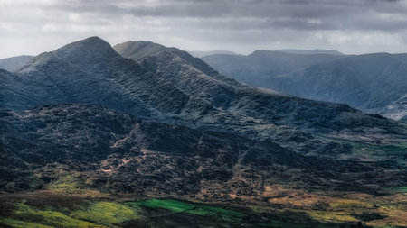 Under a dramatic sky, the Carrauntoohil Walkway offers stunning views of the hills and lush green fields of Ireland.の写真素材