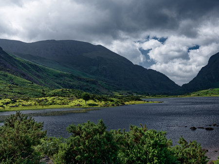Nestled between rolling hills and valleys, Black Lake offers a tranquil setting in Ireland, with cloudy skies, water's surface, creating a serene landscape.の写真素材