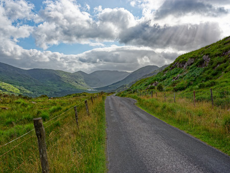 A winding road cuts through the beautiful, green landscape of Blackvalley, Ireland, framed by...
