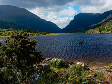 Serene landscape of Black Lake in Ireland with lush greenery and dramatic hills under cloudy skies.の写真素材