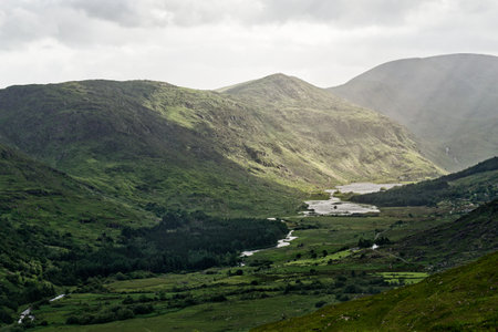 Stunning view of Blackvalley in Ireland showcasing lush green mountains and a serene river at dusk.の写真素材