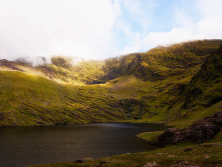 Lough callee landscape displaying calm waters surrounded by vibrant green mountains under a partly...
