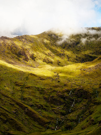 Viewing dramatic green landscape and sparse waterfalls on Carrauntoohil mountain walkway in County...