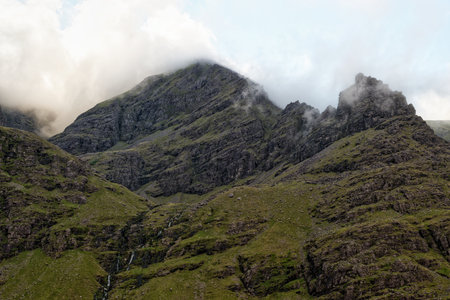 Carrauntoohil mountain is covered by clouds in County Kerry, Ireland. Moss and grass cover the mountain slopes with small waterfalls cascading down its rocky face.の写真素材