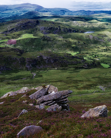 A beautiful vista encompasses rolling green hills and fields, visible from a rocky vantage point along the Coomloughra Horseshoe hiking trail in County Kerry, Ireland.の写真素材