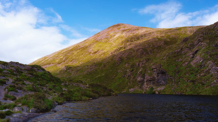 A breathtaking vista, a majestic mountain overlooking a calm lake, nature's raw power and serenity perfectly balanced.の写真素材