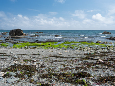 Rocky shoreline meets the ocean under a cloudy sky.の写真素材