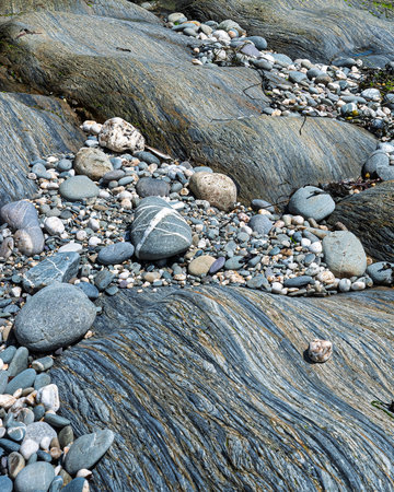 The scene shows large, smooth rocks and smaller pebbles on the shoreline. The exposed rocks display interesting textures near the ocean in West Cork.の写真素材