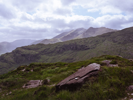 Expansive Irish landscape. Lush green hills under a soft sky. Rocks in foreground add texture.の写真素材