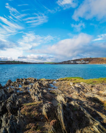 Rocky shoreline meets the blue water on a sunny day along the South Ring of Kerry, Ireland. Clouds dot the sky above the ocean.の写真素材