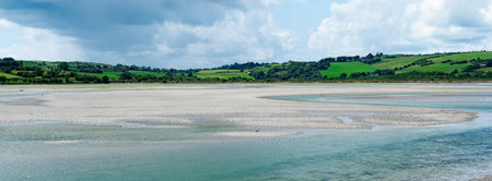 Green hills descend into the shallows of clear waters, a scene of natural wonder.