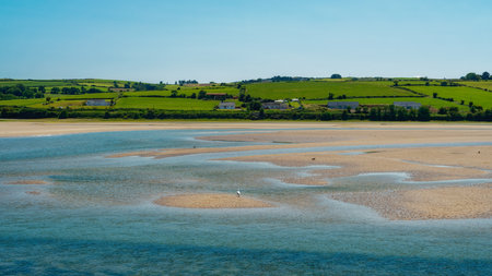 A serene landscape featuring the meeting of green hills and a tranquil sea, evoking peace.の写真素材