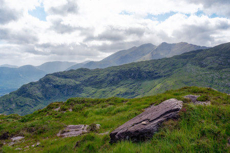 Tranquil mountain scene. Rolling hills and a peaceful atmosphere. A solitary rock rests in the grass