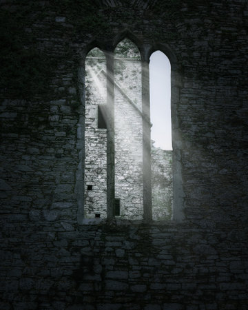Sunlight shines through the gothic window openings in a wall made of gray stone. The scene depicts the interior of an abandoned religious structure.の写真素材