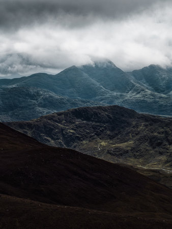 A moody landscape with layers of mountains receding into the distance under a heavy, overcast sky. A serene, yet dramatic scene unfolds.の写真素材