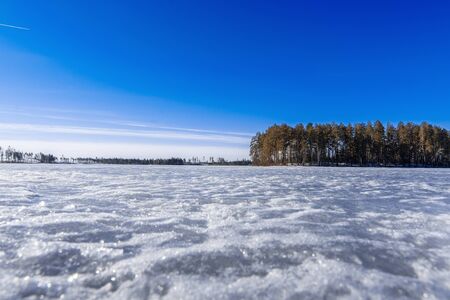 blue clear sky over the lake covered by ice in winterの写真素材