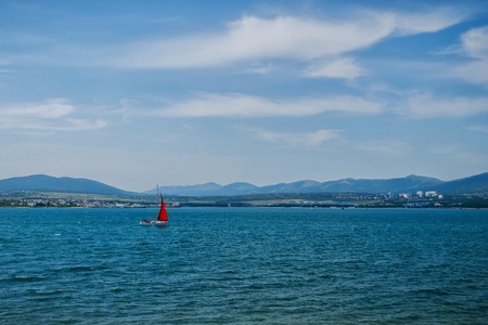 yacht with a red sail in the sea under the blue sky on a Sunny day in summerの写真素材