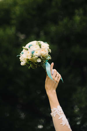 wedding bouquet of white roses in the bride's hand on green backgroundの写真素材