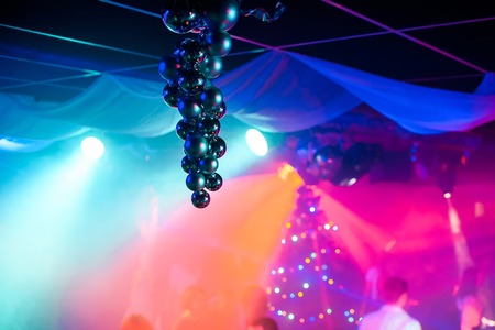 Christmas balls hanging in club with bright colored lights and blurred backgroundの写真素材