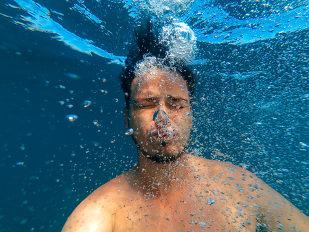 man under water sinks to bottom and releases bubbles of oxygenの写真素材