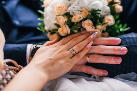 hands of the bride and groom with gold rings on the wedding day togetherの写真素材