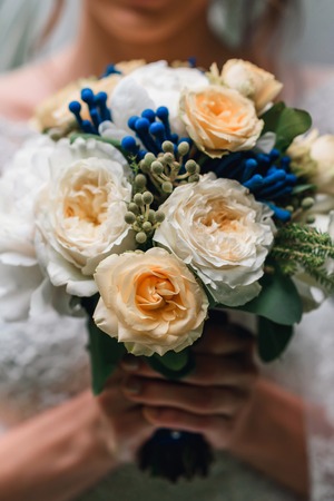wedding bouquet of white peonies and yellow roses in the hands of the bride