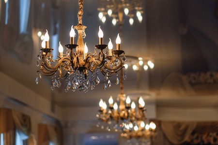 luxury vintage chandelier hanging on the ceiling with glowing lightsの写真素材