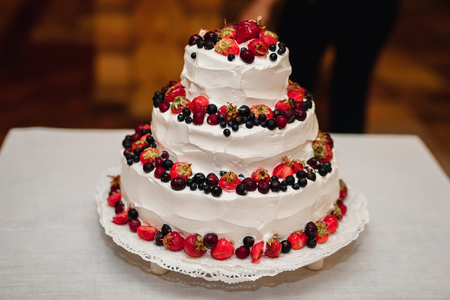 white cream wedding cake with fresh sweet strawberries, cherries, blueberries, black currantsの写真素材