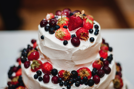 white cream wedding cake with fresh strawberries, cherries, blueberries, black currantsの写真素材