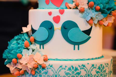 wedding cake of white blue glaze decorated with flowers and heartsの写真素材