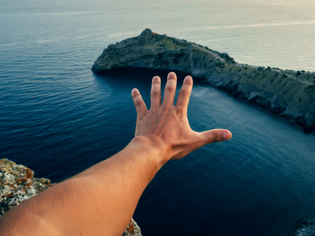 hand of a man against the sea and mountainsの写真素材