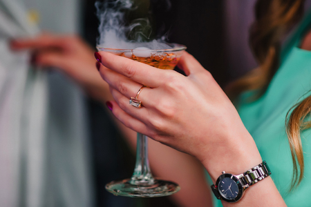 womans hand with a Martini glass with bubbles and steamの写真素材