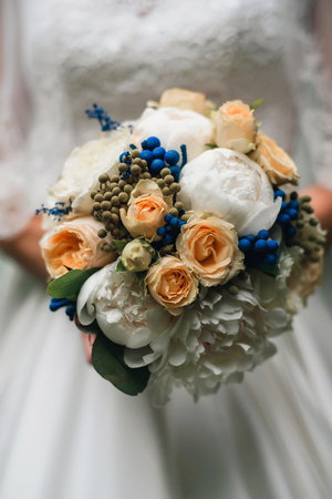 wedding bouquet of white peonies and yellow roses in the hands of the brideの写真素材