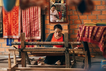 MUI NE, VIETNAM - MARCH 6, 2017: Women weavers work traditional looms for silkのeditorial素材