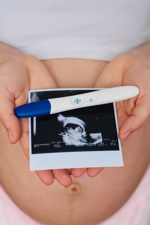 ultrasound picture and positive pregnancy test in the hands of a pregnant girlの写真素材