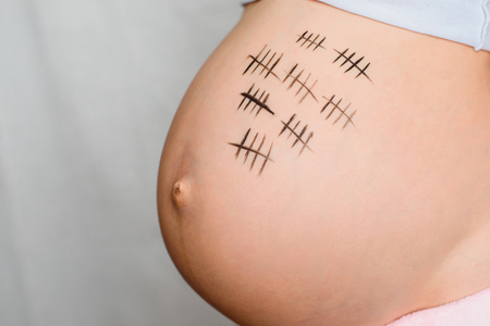belly of a pregnant girl with painted paints for a period of pregnancyの写真素材