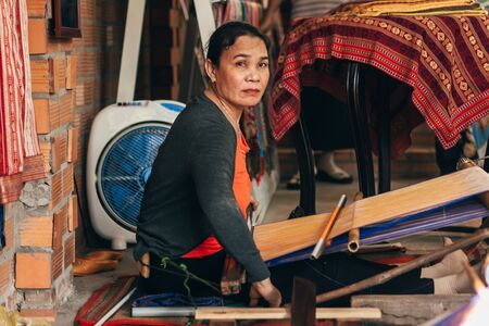 MUI NE, VIETNAM - MARCH 6, 2017: Female weaver working at a traditional weaving machines for silkのeditorial素材