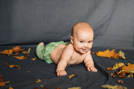 newborn baby cute happy boy lying on autumn backgroundの写真素材